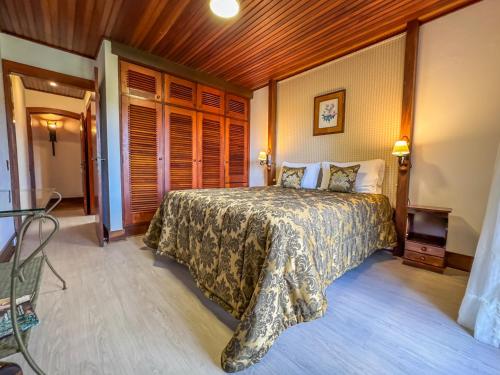 a bedroom with a bed and a wooden ceiling at Mansão Nacional Inn in Campos do Jordão