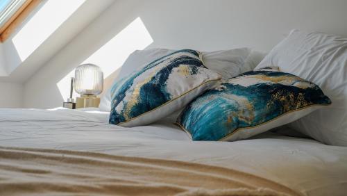 a bed with blue and white pillows on it at Spacious Bromley Home w Free parking and Outside Dining in Bromley