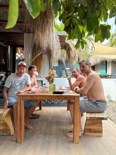 un grupo de hombres sentados en una mesa bajo un paraguas en KokohauBungalows, en Santa Verónica