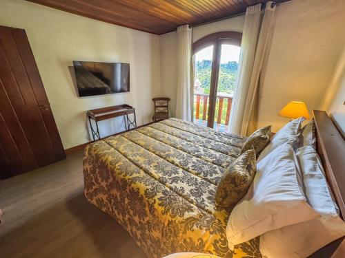 a bedroom with a large bed and a window at Mansão Nacional Inn in Campos do Jordão