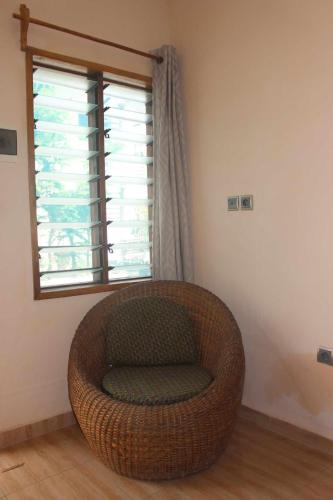 a wicker chair in a room with a window at Maison Tikani in Cotonou
