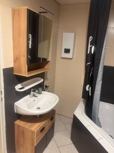 a bathroom with a sink and a mirror and a tub at Ferienwohnung Klosterblick in Bastheim