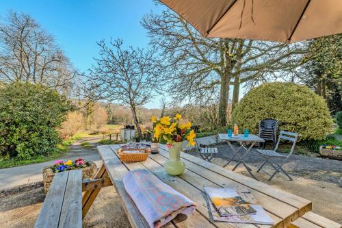 a picnic table with a vase of flowers and an umbrella at Les gîtes de la vallée du rivoal in Lopérec