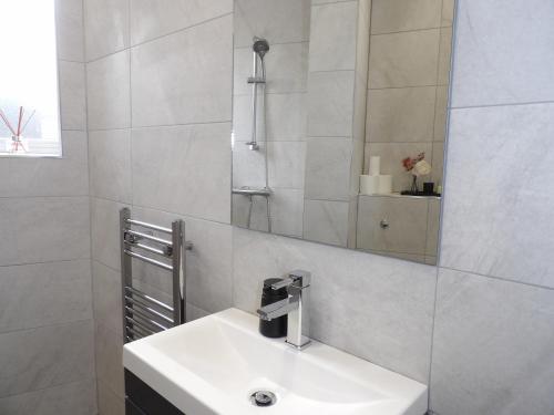 ein Badezimmer mit einem weißen Waschbecken und einem Spiegel in der Unterkunft City Convenience, Calm Comfort-- A Stylish One-Bedroom Retreat Just 3 Stops from the Heart of the City in Edinburgh