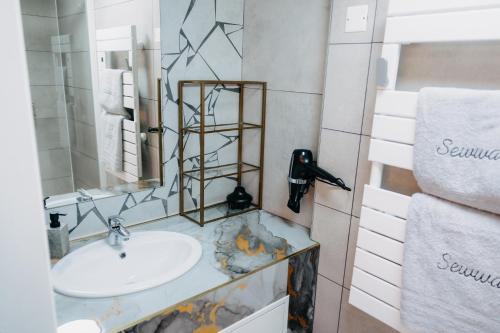 a bathroom with a sink and a mirror and towels at Sewwa Guest House in Sélestat