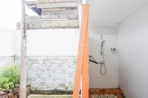a shower in a room with a brick wall at Kampung 168 in Jimbaran