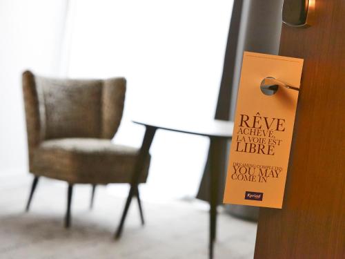 a chair and a table with a sign on a door at Kyriad Troyes Centre in Troyes