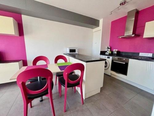 une cuisine avec des murs roses, une table et des chaises dans l'établissement Quiberon - 2 pièces cosy, terrasse, proche plage, animaux admis - FR-1-478-32, à Quiberon