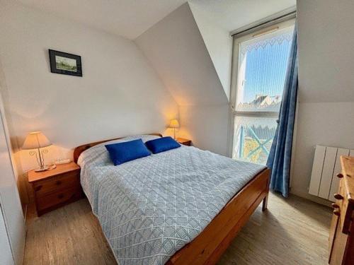 une chambre avec un lit avec des oreillers bleus et une fenêtre dans l'établissement Maison à Quiberon 3 pièces avec piscine, proche plage et commerces - FR-1-478-60, à Quiberon