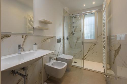 Un baño con inodoro, lavabo y ducha. en GOLDEN LUXE - New Style in Forte dei Marmi Private Parking, en Forte dei Marmi