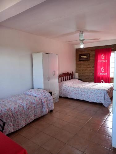 two beds in a room with red curtains at Terraza al Mar in Las Grutas