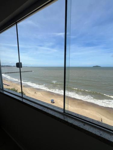 a view of a beach from a window at Pé na areia incrível in Piçarras
