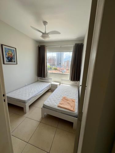 a bedroom with two beds and a window at Pé na areia incrível in Piçarras