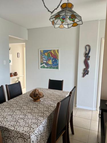 a dining room with a table and a chandelier at Pé na areia incrível in Piçarras