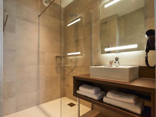 a bathroom with a sink and a glass shower at Kyriad Troyes Centre in Troyes