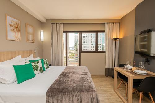 a hotel room with a bed and a desk and a television at APS - Alpha Stay By Anora Spaces in Barueri