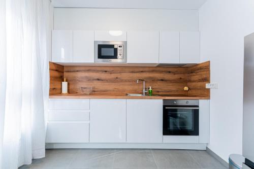 eine Küche mit weißen Schränken und einer Mikrowelle in der Unterkunft Flex SelfCheckIns 100 - Zagreb - 2 Bedrooms - Parking - Loggia in Velika Mlaka