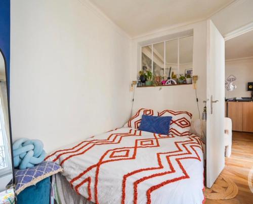 sypialnia z łóżkiem z czerwoną i białą kołdrą w obiekcie Appartement cosy quatier Gambetta w Paryżu