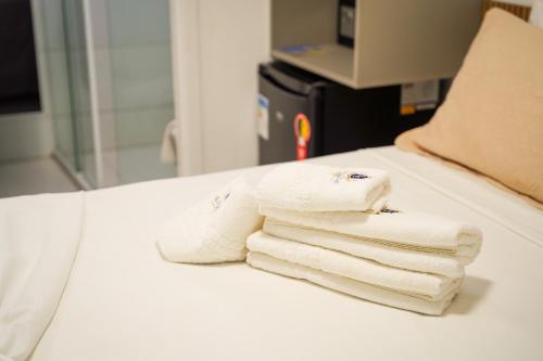 three white towels are stacked on a bed at EL SHADDAI HOTEL in João Pessoa