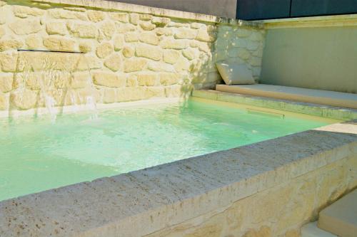 une piscine d'eau dans un mur en pierre dans l'établissement La Villa Ulysse, à Maussane-les-Alpilles
