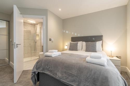 a bedroom with a large bed and a walk in shower at Bond House by Celador Apartments in Reading