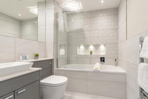 a white bathroom with a tub and a toilet and a sink at Bond House by Celador Apartments in Reading