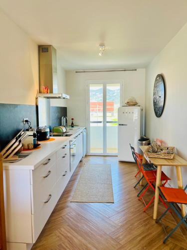 une cuisine avec une table et un réfrigérateur blanc dans l'établissement Belle vue sur le port & Parking privé, à Saint-Florent