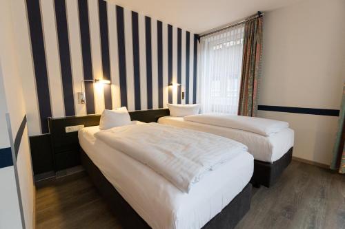 a hotel room with two beds and a window at Hotel DH VEC in Vechta