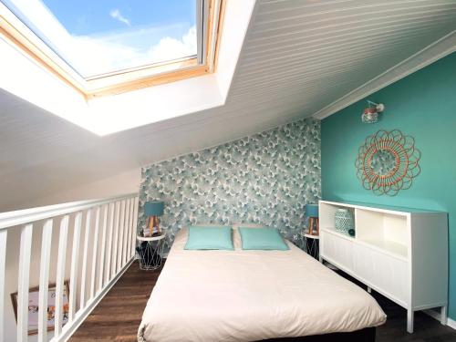 une chambre avec un lit et une lucarne dans l'établissement Le doux refuge aperçu mer, à Les Sables-dʼOlonne