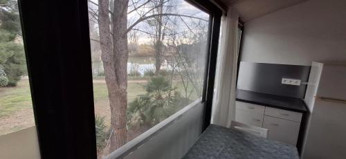 Cette chambre dispose d'une grande fenêtre offrant une vue sur un arbre. dans l'établissement Studio Village Camarguais, à Arles