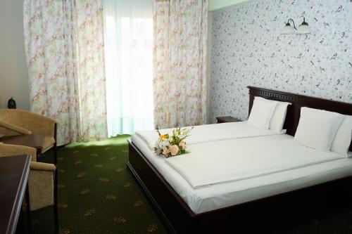 a bedroom with a bed with a flower arrangement on it at Popasul Caprioarei in Pădureni