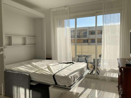 une chambre avec un lit et un balcon dans l'établissement Appartement T2 Lumineux à Balaruc-les-Bains, Proche Thermes, Parking, Wifi, 2 Étoiles - FR-1-553-130, à Balaruc-les-Bains