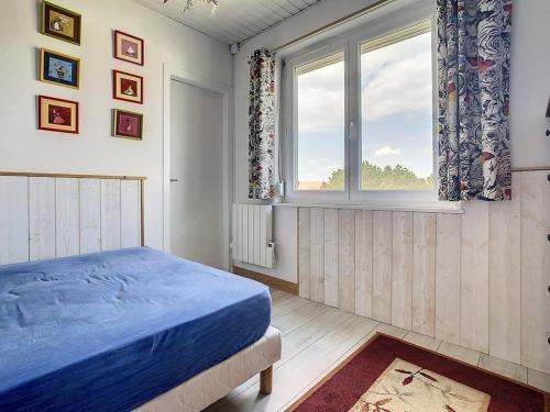 une chambre avec un lit bleu et une fenêtre dans l'établissement Appartement 2 chambres proche mer - 1er étage, parking, cuisine équipée, TV et calme assuré - FR-1-236-77, à Stella-Plage