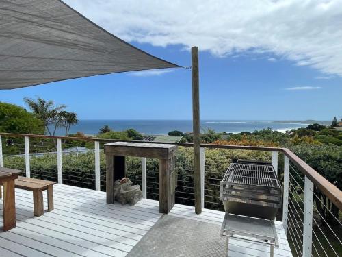 a deck with a grill and a table and a bench at LaVidaLekker in Brenton-on-Sea