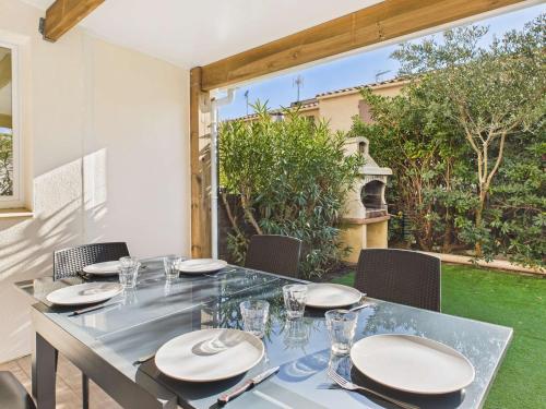 - une table à manger avec des assiettes et des verres sur la terrasse dans l'établissement Appartement duplex climatisé avec terrasse, 1 chambre, parking privé, proche plage - FR-1-326-559, à Marseillan