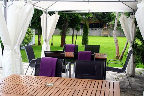 una mesa de madera y sillas bajo un dosel blanco en Hotel George, en Nadarzyn