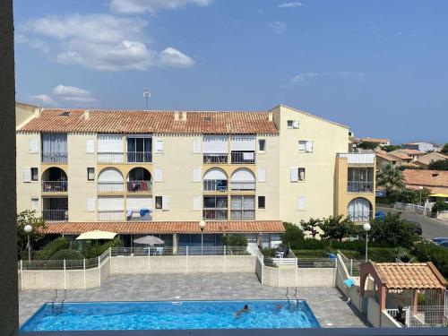 un immeuble avec une piscine devant un immeuble dans l'établissement Appartement 2 pièces avec mezzanine, piscine et parking à Narbonne Plage - FR-1-229B-63, à Narbonne