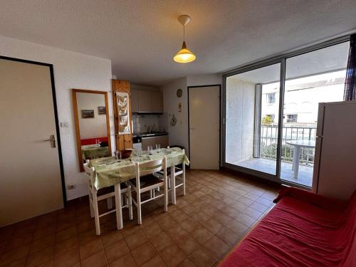 un salon avec une table et une cuisine dans l'établissement Appartement 2 pièces avec loggia, piscine et parking privé à 250m des commerces et proche plage - FR-1-229B-74, à Narbonne