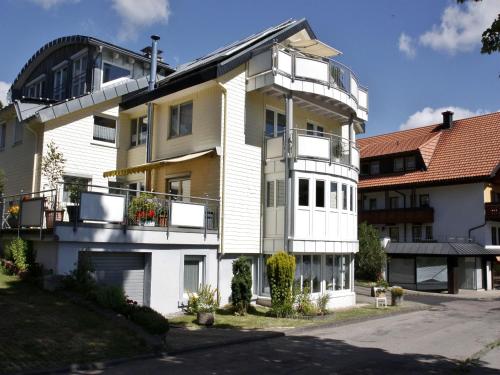 ein weißes und gelbes Gebäude mit einem Balkon in der Unterkunft Ferienwohnungen Uhren Allgaier in Schönwald