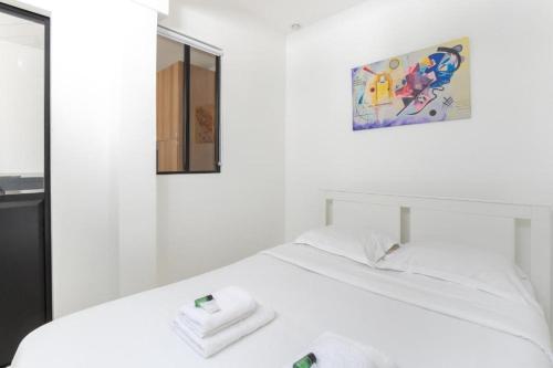 un lit blanc avec deux serviettes dessus dans l'établissement Divry - Montparnasse Superbe Appartement 4P, à Paris