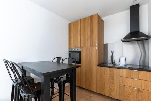 une cuisine avec une table noire et des placards en bois dans l'établissement Divry - Montparnasse Superbe Appartement 4P, à Paris