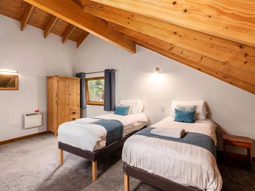 two beds in a room with wooden ceilings at Strathyre, Ben Ledi Cabins - Forest Holidays in Callander