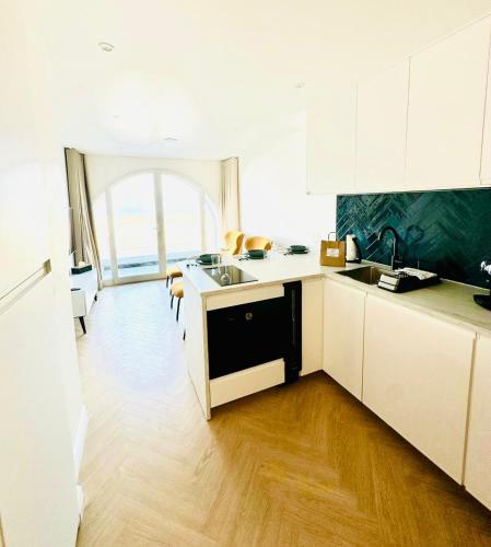 une cuisine avec des placards blancs et une grande fenêtre dans l'établissement Le One - Villa la Potinière - mer, à Dunkerque