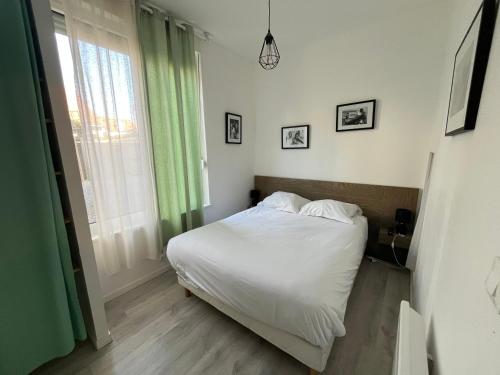 une chambre avec un lit avec des draps blancs et une fenêtre dans l'établissement Appartement 2 pers hyper centre, à Le Touquet-Paris-Plage