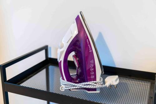 a purple and white hair dryer on a shelf at 2 Bedroom Apartment in Birmingham City-centre with Free Parking in Birmingham