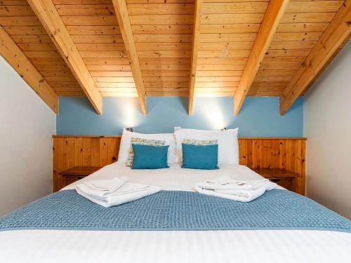 a bedroom with a bed with blue walls and wooden ceilings at Strathyre, Ben Ledi Cabins - Forest Holidays in Callander