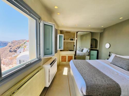 Un dormitorio con una cama y una ventana grande. en SantorOia Luxury Suites by Caldera Houses, en Oia