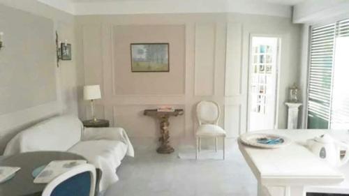 un salon blanc avec un canapé et une table dans l'établissement Appartement jardin, à Cannes