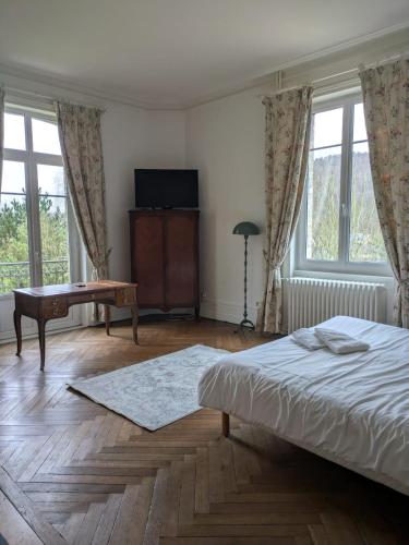 une chambre avec un lit, un bureau et des fenêtres dans l'établissement Château de Branville, à Saint-Aubin-Epinay