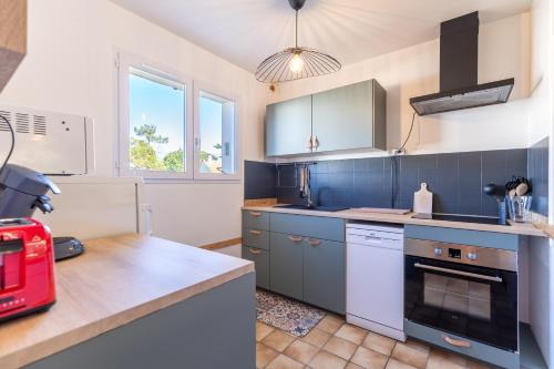 une cuisine avec des armoires bleues et un appareil rouge dans l'établissement Le 5 Mimosas - Plage à 600m garage, à Saint-Jean-de-Monts